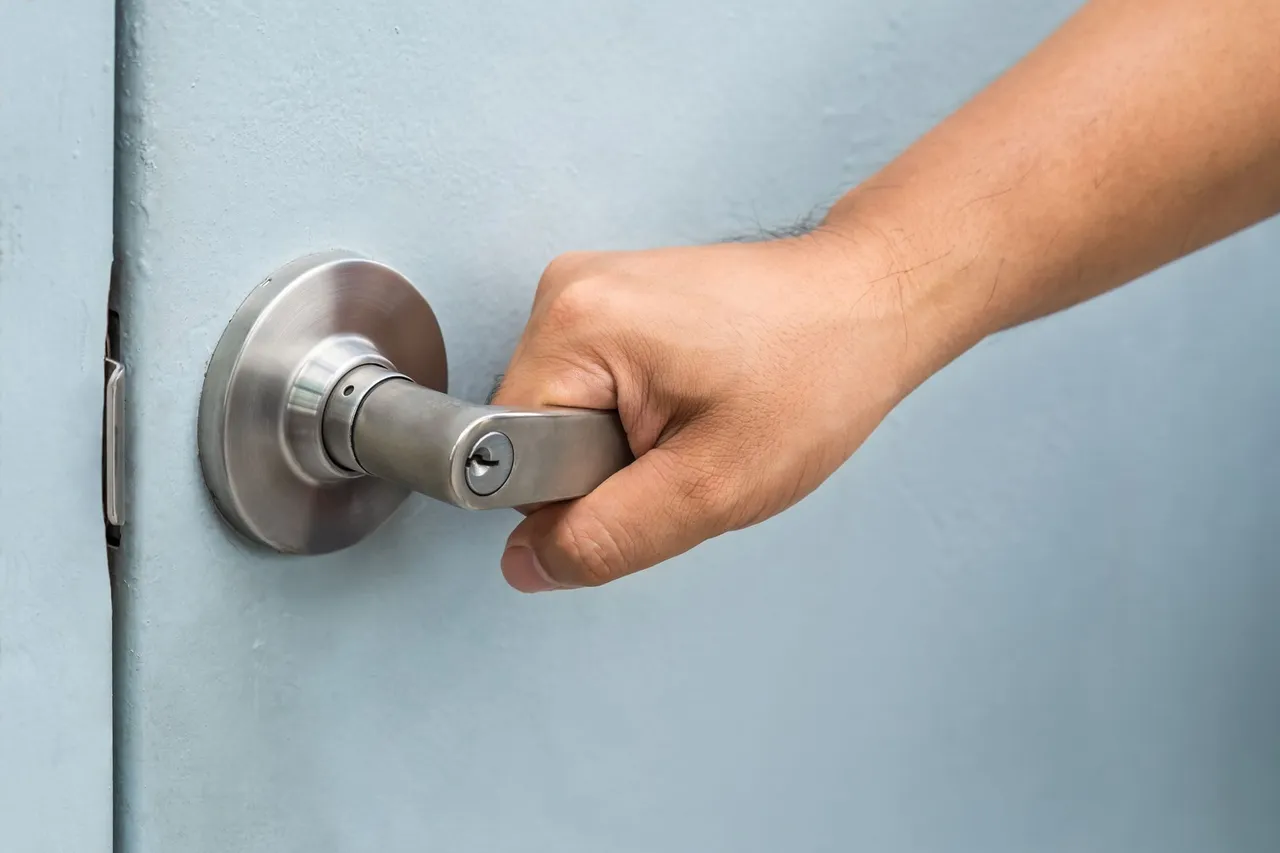 A person is opening a car door with a key.