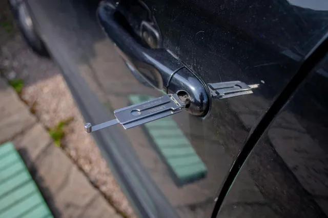 A person is opening a car door with a key.